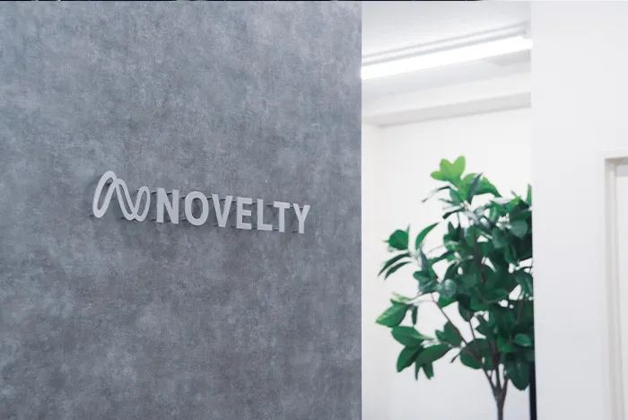 グレーの壁面にNOVELTYのロゴが掲げられたオフィスエントランス。