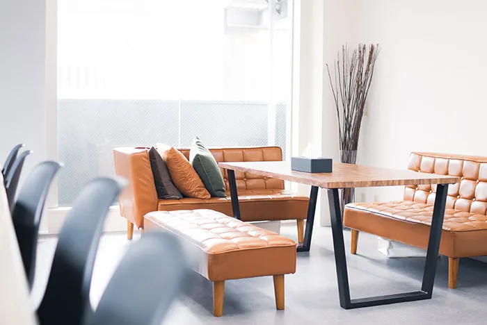 木製のテーブルと革張りのソファがある打ち合わせスペース。大きな窓から光が差し込んでいる。