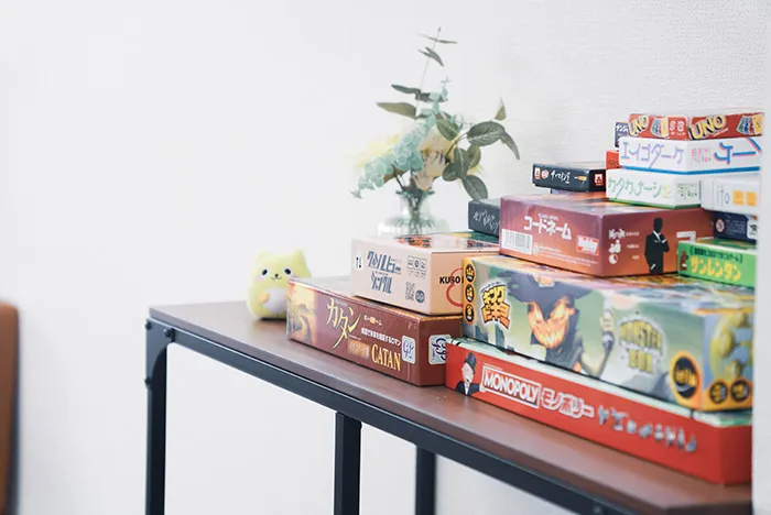 カタンやモノポリーなどさまざまなボードゲームの箱が積まれている棚。